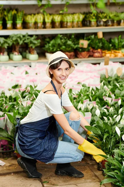 庭の保育園で植物と一緒に働く制服を着たかなり笑顔の若い女性 — ストック写真