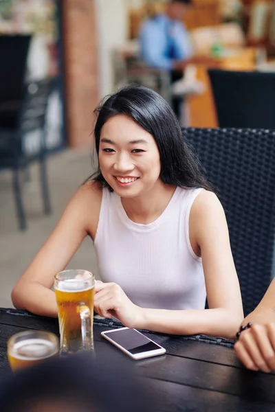 Feliz Asiática Joven Sentada Mesa Sonriendo Mientras Bebe Cerveza Cafetería —  Fotos de Stock