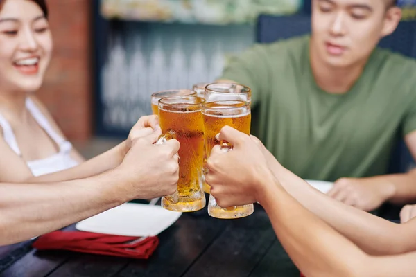 Close Young People Sitting Table Holding Glasses Beer Toasting — Stock Photo, Image