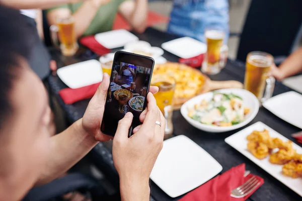 Detailní Záběr Mladého Muže Držícího Mobilní Telefon Fotografujícího Jídlo Stole — Stock fotografie