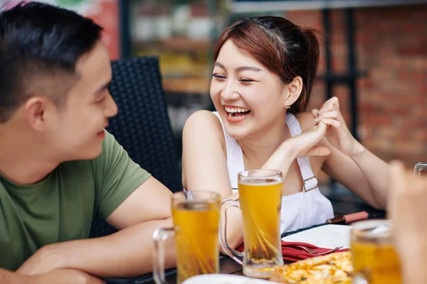 亚洲的年轻女子一边坐着一边笑 一边与年轻男子交谈 他们一起在咖啡馆里喝啤酒 — 图库照片
