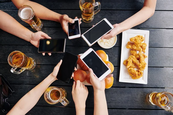食品とテーブルで携帯電話を保持している友人の高い角度ビュー — ストック写真
