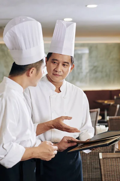 Chef Asiático Uniforme Apontando Para Menu Discutindo Junto Com Seu — Fotografia de Stock