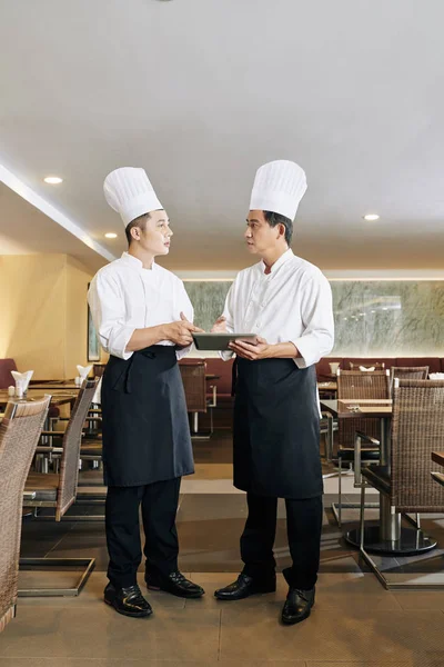 Dois Colegas Uniforme Chef Usando Tablet Digital Discutindo Cardápio Para — Fotografia de Stock