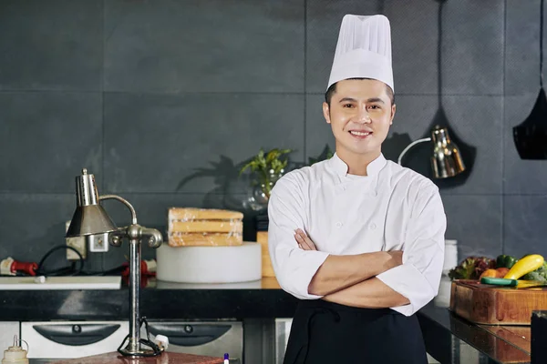 站在厨房时 亚洲年轻厨师双臂交叉地站在镜头前微笑的画像 — 图库照片