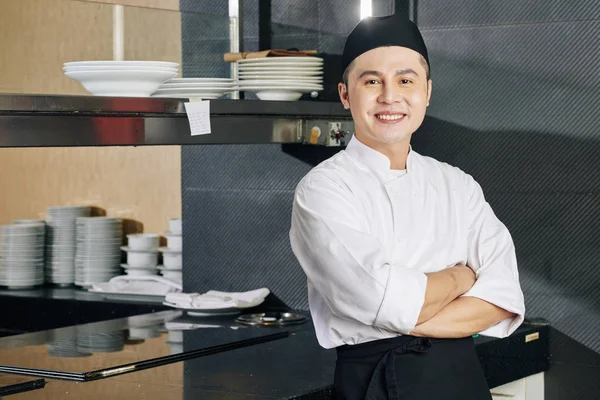 站在厨房时 身穿制服的亚洲年轻厨师的画像 双手交叉 对着相机微笑 — 图库照片