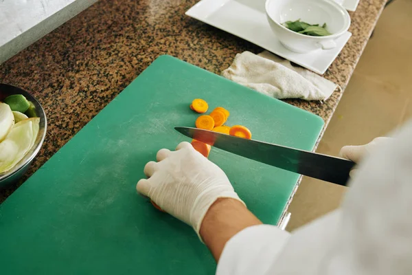 Close Cozinheiro Luvas Proteção Cortando Cenoura Com Faca Tábua Corte — Fotografia de Stock