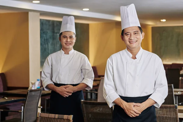 亚洲成熟厨师的画像 身穿制服 与同事站在餐厅后面对着镜头微笑 — 图库照片