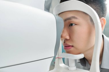 Asyalı genç bir hasta hastanede gözlerini özel tıbbi malzemelerle tedavi ediyor.