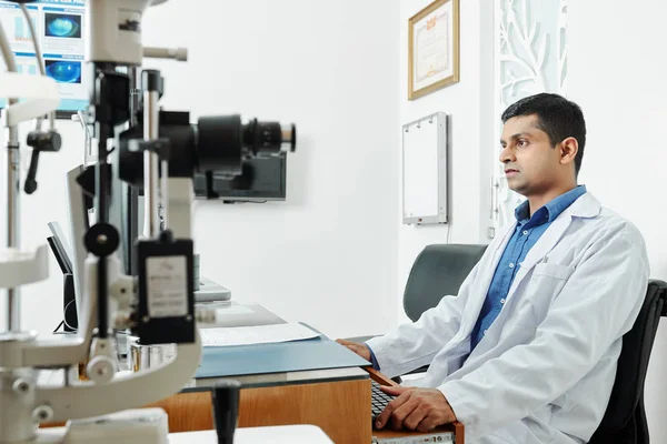 Серьезный Индиец Сидящий Столом Работающий Медицинским Оборудованием Офисе — стоковое фото