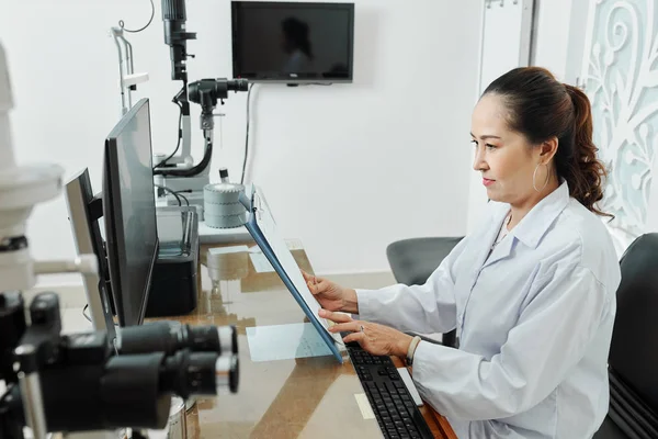 Beyaz Önlüklü Ciddi Bir Asyalı Kadın Doktor Yerinde Oturuyor Ziyaretinden — Stok fotoğraf