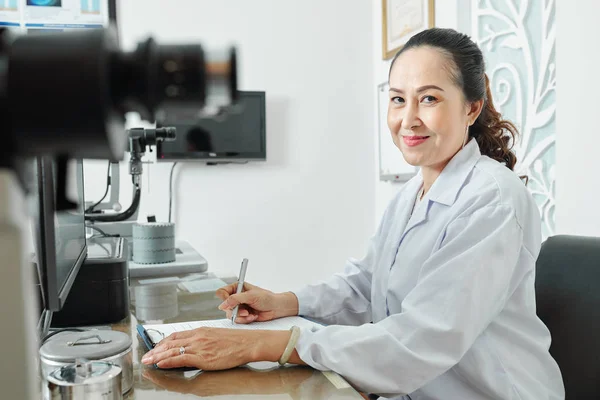 Retrato Una Optometrista Asiática Sentada Mesa Mirando Cámara Mientras Trabaja —  Fotos de Stock