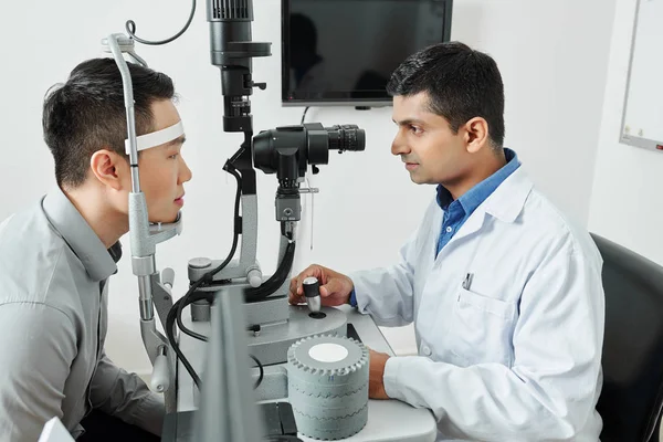 Beyaz Önlüklü Hintli Doktor Özel Mikroskopa Bakıyor Hastasının Ofisteki Görüşünü — Stok fotoğraf