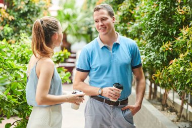 Yakışıklı, kendine güvenen genç bir adam kahve içer, parkta genç ve güzel bir bayanla flört eder.