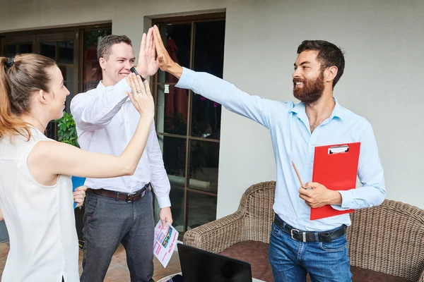 Team of happy business people giving each other high five after successful meeting in outdoor cafe