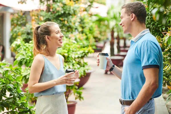 公園に立ってコーヒーを飲みながら ニュースや冗談を話し合う陽気な若者と女性 — ストック写真