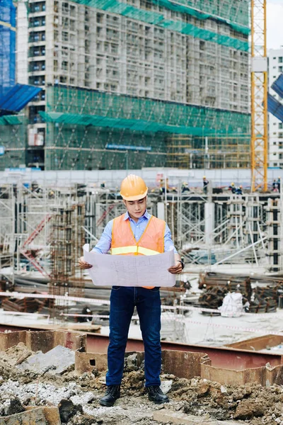 Jonge Vietnamese Bouwkundig Ingenieur Staat Bouwplaats Wolkenkrabber Onderzoekt Blauwdruk — Stockfoto