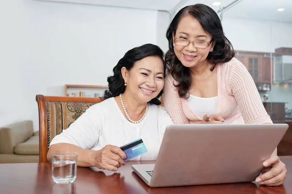ラップトップコンピュータを一緒に使用し 自宅でクレジットカードでオンラインで購入する2人のアジアのシニア女性 — ストック写真
