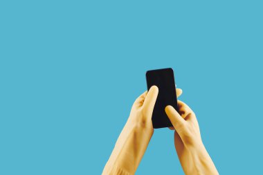 Sarı lastik eldivenli ev hanımı akıllı telefonda mobil uygulama kullanıyor, mavi renkte izole edilmiş.