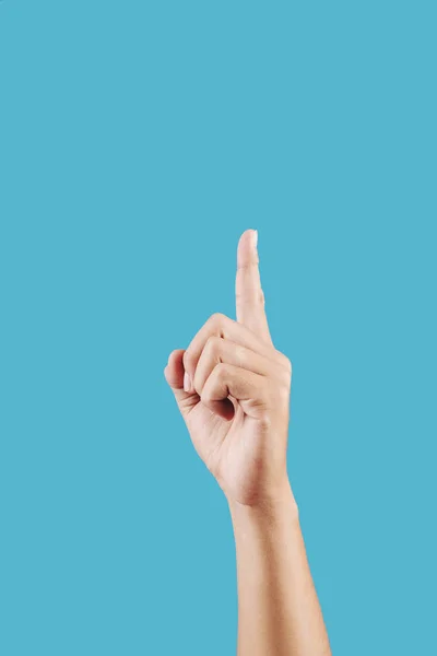 Hand of person pointing up in the air with index finger, isolated on light blue