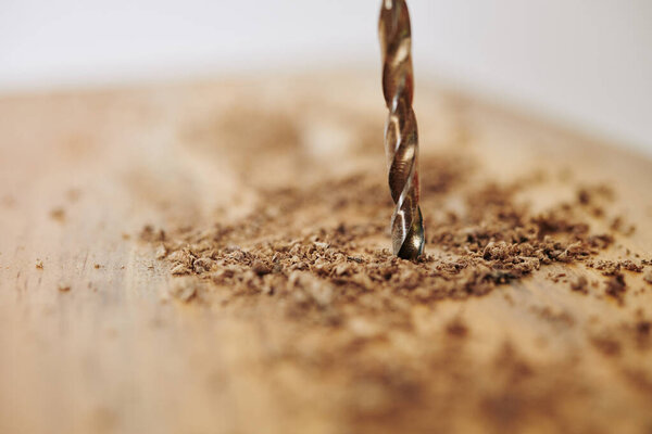 Close-up image of big drill making hole in wooden block, selective focus