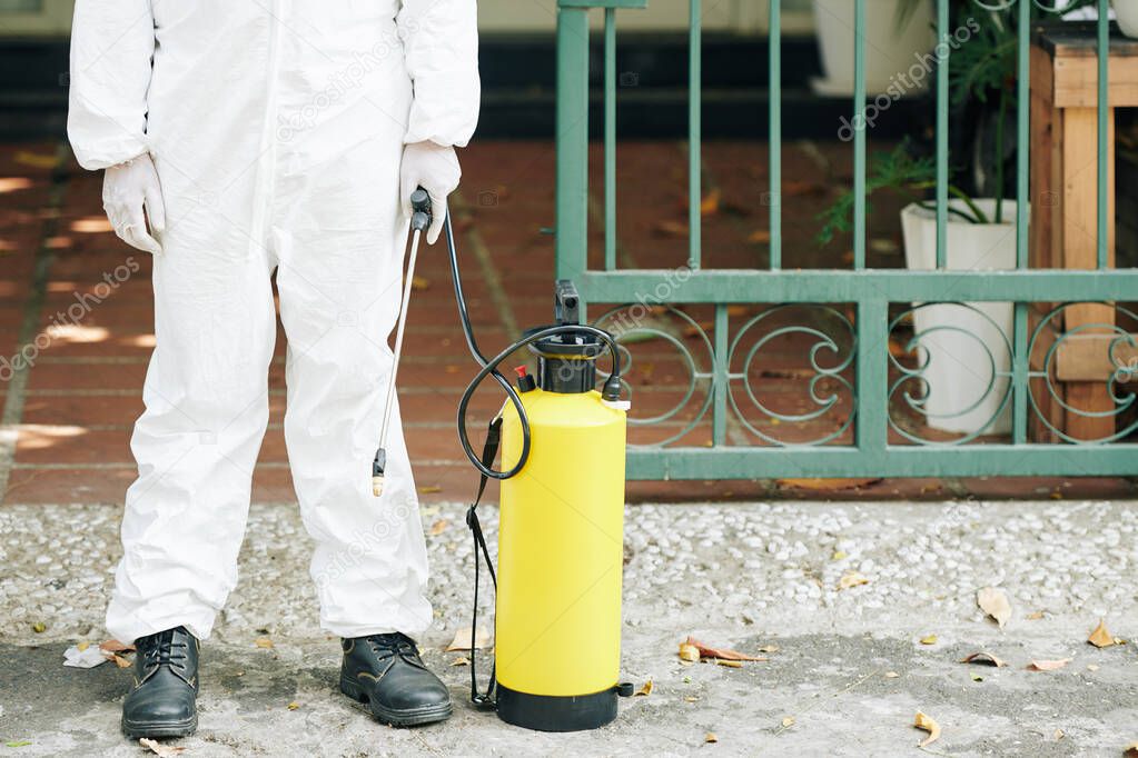 Cropped image of technician in protective coverall spraying activities to prevent spread of corona virus in the street