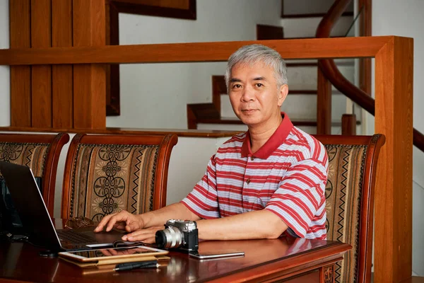 成熟的中国摄影师在家里的笔记本电脑上工作 在笔记本电脑上编辑照片 — 图库照片