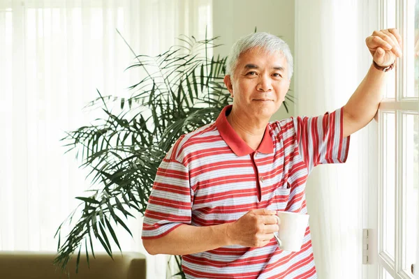 Mutlu Asyalı Adam Pencerede Duruyor Evde Sabah Kahvesini Içiyor — Stok fotoğraf