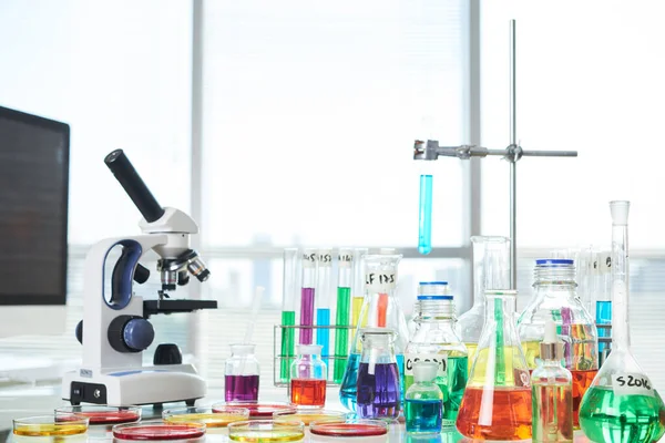 医学实验室桌上装有五颜六色液体的显微镜 试管和培养皿 — 图库照片