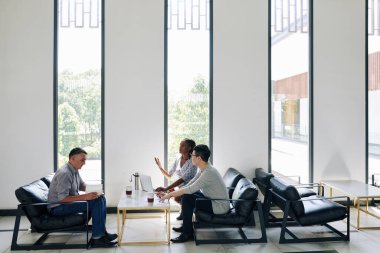 İş ortakları proje ve sözleşme ayrıntılarını görüşmek üzere dinlenme alanında toplanıyorlar.