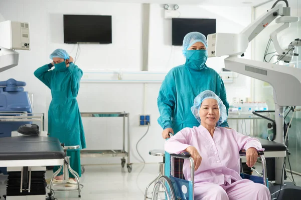 Hemşire Tekerlekli Sandalyedeki Kıdemli Hastayı Göz Hekimliği Kliniğindeki Ameliyathaneye Götürüyor — Stok fotoğraf