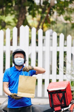 Tıbbi maskeli pozitif kurye, salgın sırasında evde kalan müşterilere ücretsiz yemek dağıtımı sağlıyor.