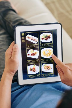 Tablet bilgisayarı olan bir adam restorandan siparişe kadar yemek seçiyor.
