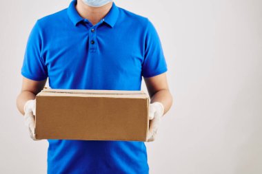 Paket teslim edilirken maske takan mavi tişörtlü bir kurye.