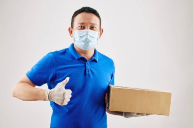 Pozitif Asyalı teslimatçı elinde karton pizza kutusuyla baş parmağını kaldırıyor.