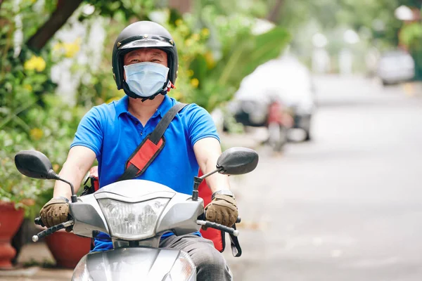 在流感大流行期间 携带头盔和医疗面罩骑着摩托车运送食物给呆在家里的顾客 — 图库照片