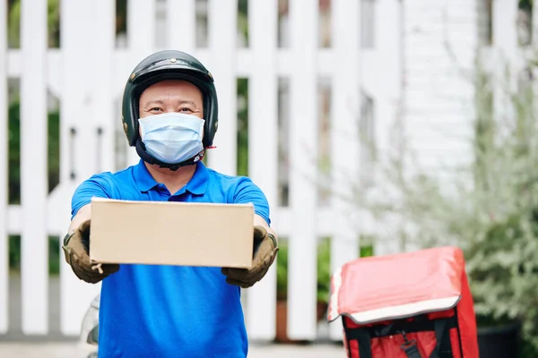 戴着医疗面罩微笑的亚洲送货员送纸盒 — 图库照片