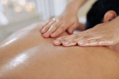 Müşteriye sıcak organik yağ ile masaj yapan masözün yakın plan görüntüsü