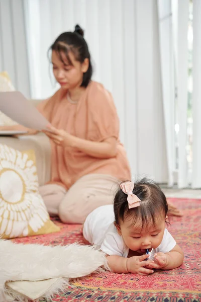 Liten Flicka Tugga Barnsjukdomar Leksak När Hennes Mamma Arbetar Med — Stockfoto