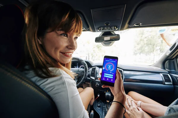 Cheerful Motorista Bonito Carro Verificando Aplicativo Carregador Inteligente Seu Smartphone — Fotografia de Stock