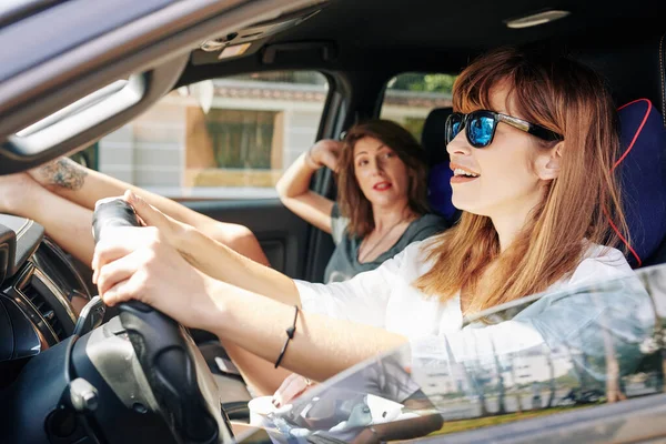 Güneş Gözlüklü Neşeli Genç Kadın Araba Sürerken Arkadaşıyla Konuşuyor — Stok fotoğraf