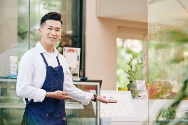 Vietnamlı genç bir adamın portresi müşterilerini kafesinde karşılıyor.