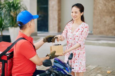 Scooter 'daki kurye, genç gülen müşteriye yiyecek getiriyor.