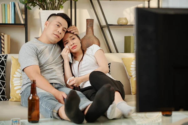 Young couple crying when watching sad drama movie on tv at home