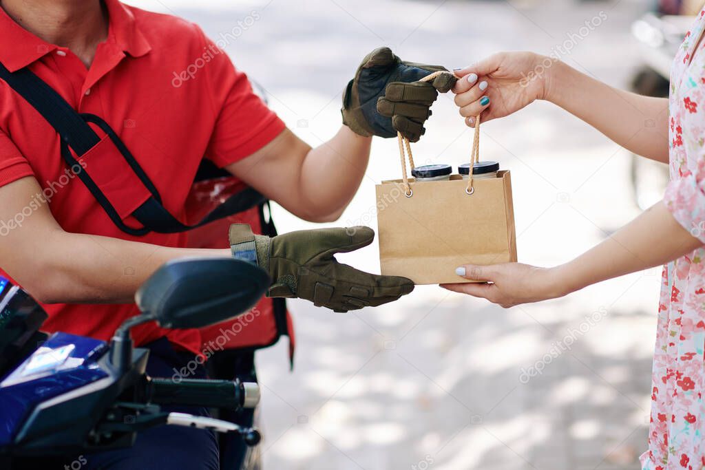 Hands of courier giving order of natural organic yogurt to female client