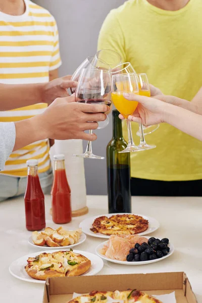 キッチンテーブルに集まった仲間たちとオレンジジュースと赤ワインのクリーニンググラス — ストック写真
