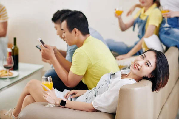 在家庭聚会上 漂亮的年轻亚洲女人躺在沙发上 喝着一杯橙汁 — 图库照片