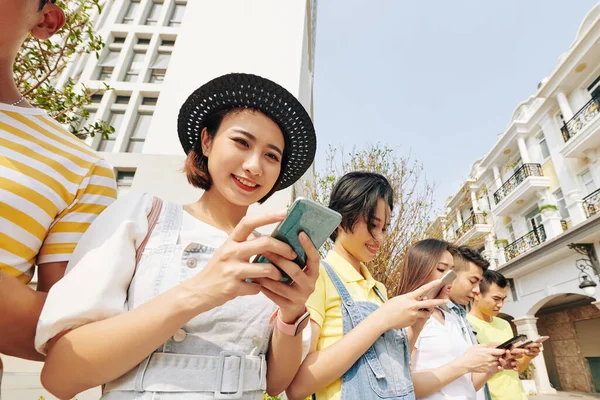 友人と屋外に立つとき かなり若い女性はソーシャルメディアでニュースをチェックします — ストック写真