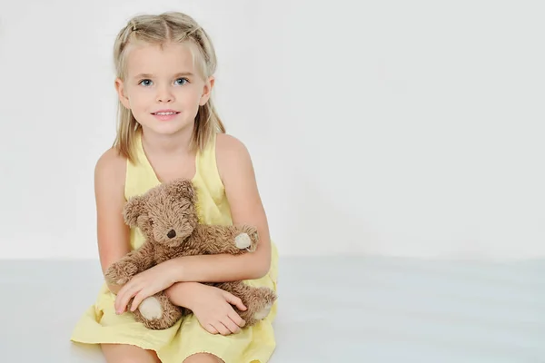 照片上的小女孩面带微笑 泰迪熊坐在地板上 看着相机 — 图库照片