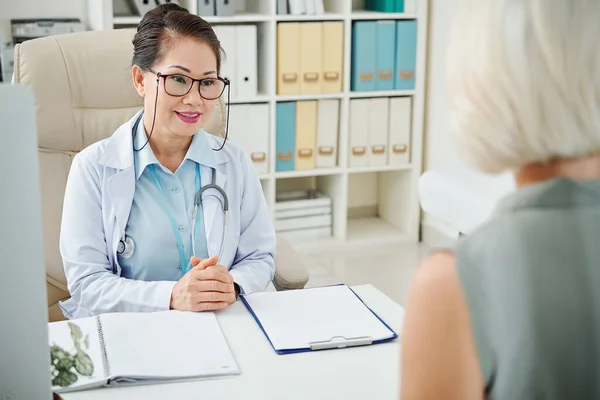 Médico General Sonriente Que Escucha Las Quejas Una Paciente Femenina —  Fotos de Stock